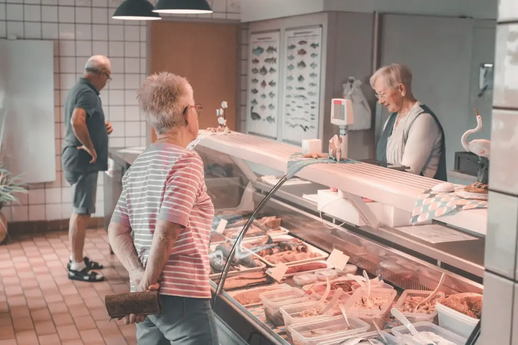 Zwei Kunden vor der gekühlten Auslage im Hofladen der Fischzucht Kroppen